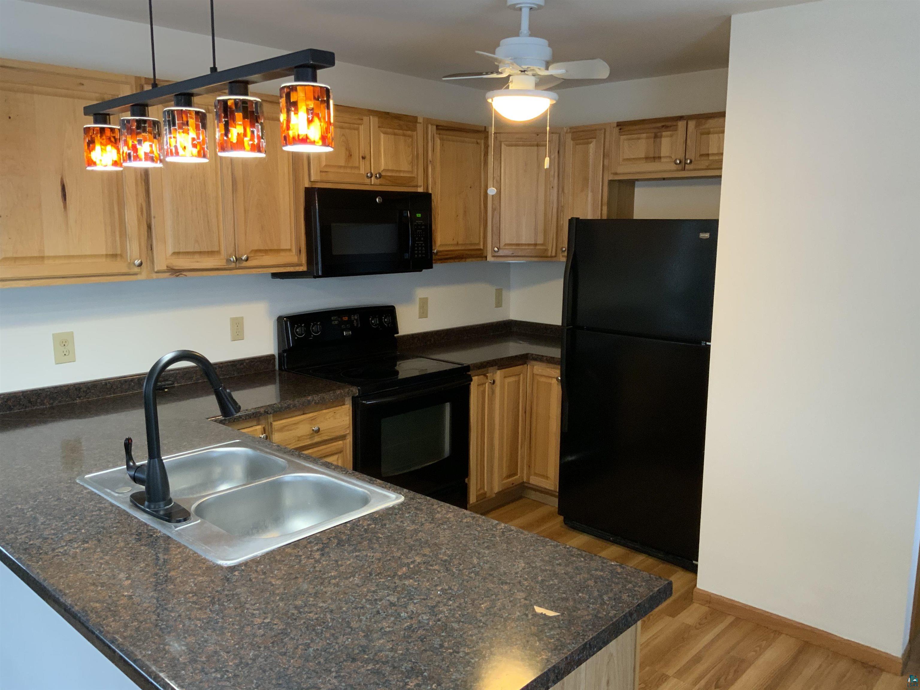 904 Spring Lake Road Cloquet, MN 55720 - Photo 3 of 14 Kitchen featuring black appliances, sink, light hardwood / wood-style floors, decorative light fixtures, and ceiling fan