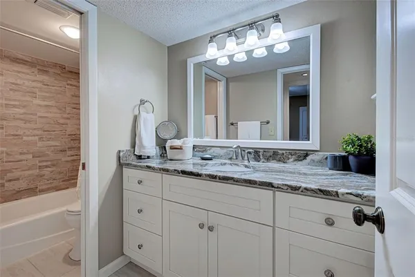 a bathroom with a granite countertop sink a large mirror and a bathtub