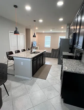 a large kitchen with stainless steel appliances granite countertop a sink counter space cabinets and a fireplace