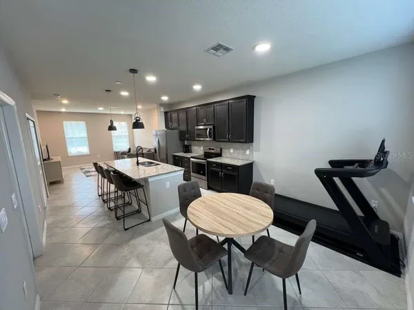 a kitchen with a dining table chairs and a refrigerator