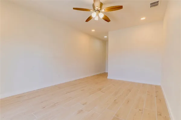an empty room with a ceiling fan and wooden floor