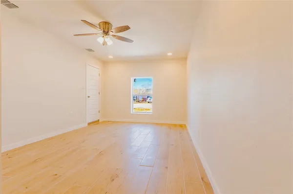 an empty room with a ceiling fan and window