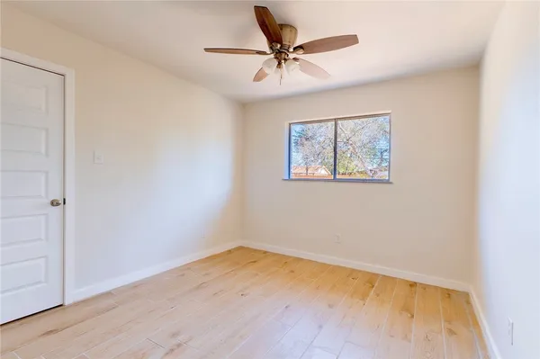 an empty room with a window and a ceiling fan