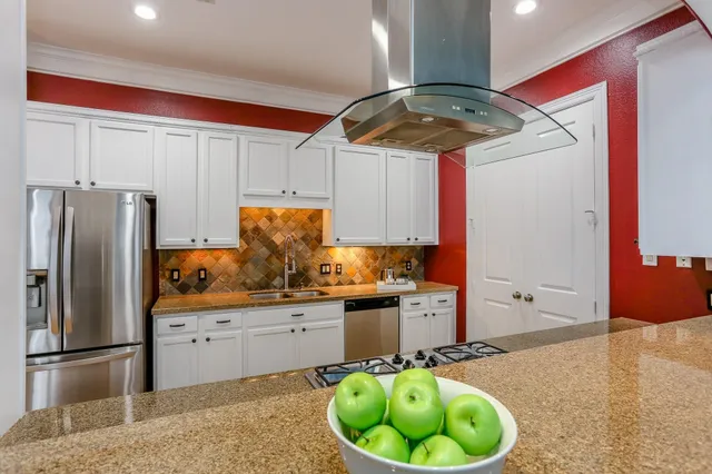a kitchen with stainless steel appliances granite countertop a sink a refrigerator and a stove top oven