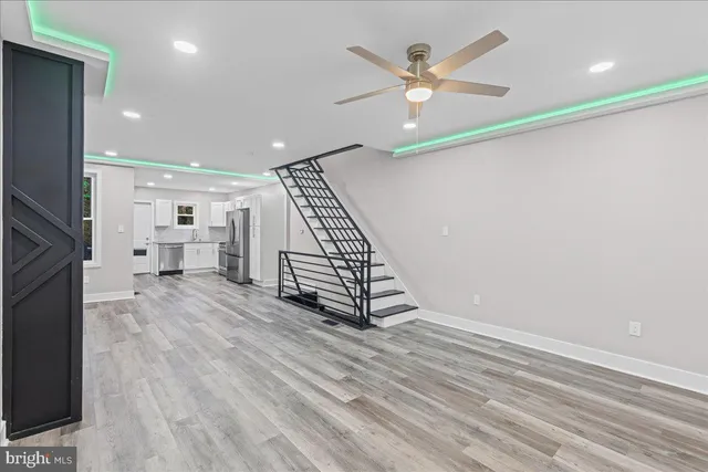 an empty room with wooden floor a ceiling fan and windows