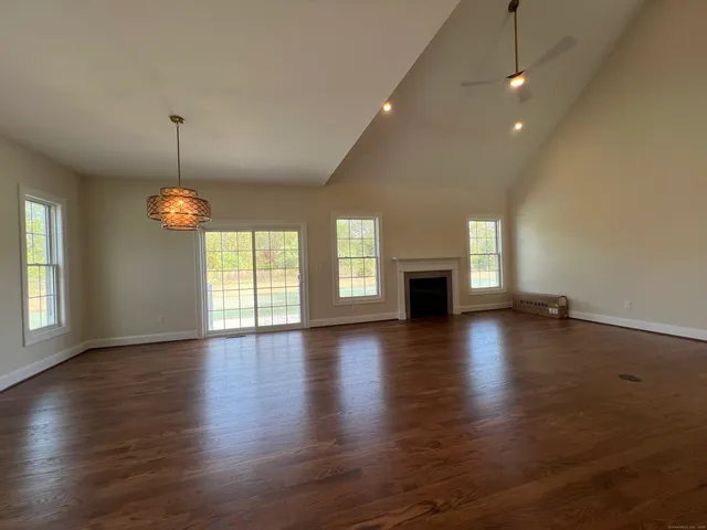 an empty room with wooden floor fireplace and windows