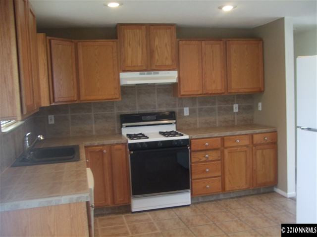10012 Albite Street Reno, NV 89506 - Photo 2 of 9 a kitchen with granite countertop a stove top oven sink and cabinets