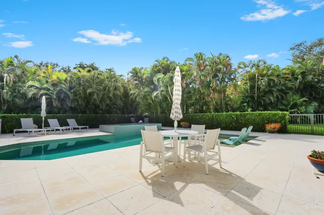 a view of a white house with a big yard plants and palm trees