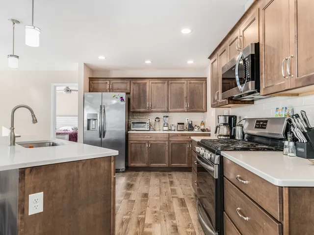 a kitchen with stainless steel appliances granite countertop a sink a stove a refrigerator and cabinets