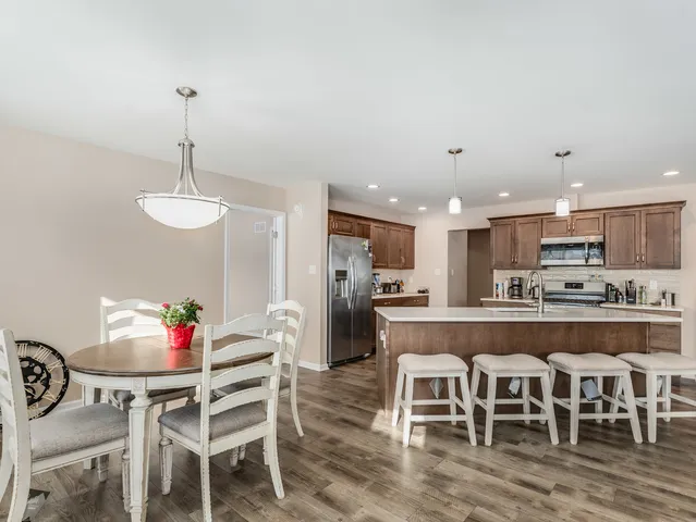 a kitchen with stainless steel appliances granite countertop a dining table chairs and white cabinets