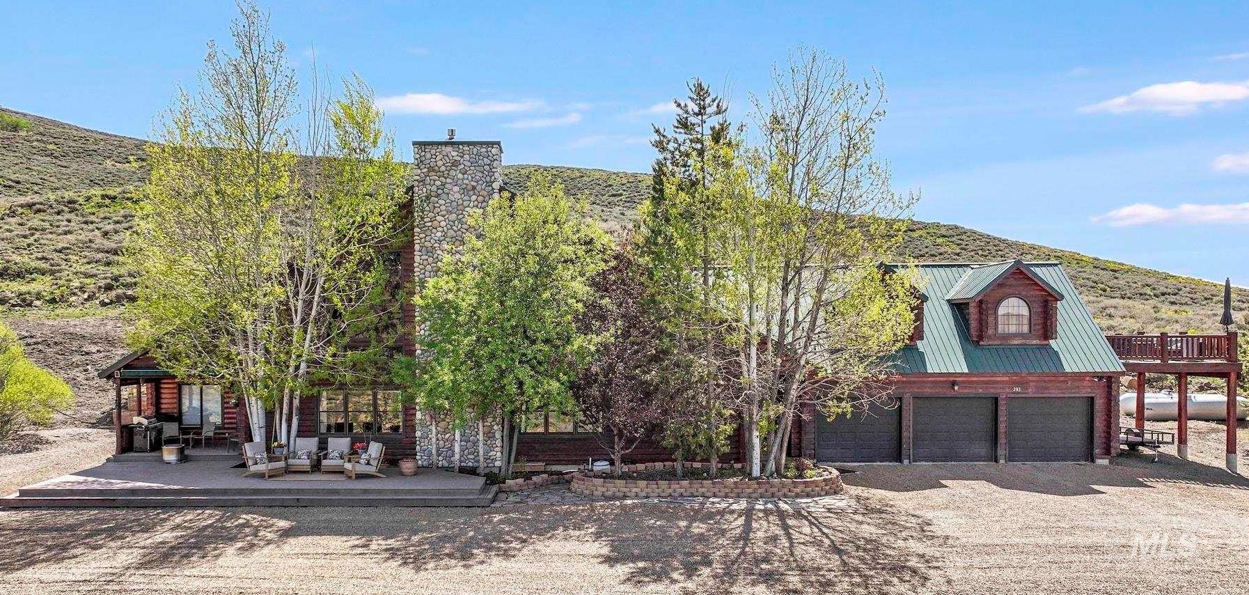 Back of property with driveway, an attached garage, and a metal roof