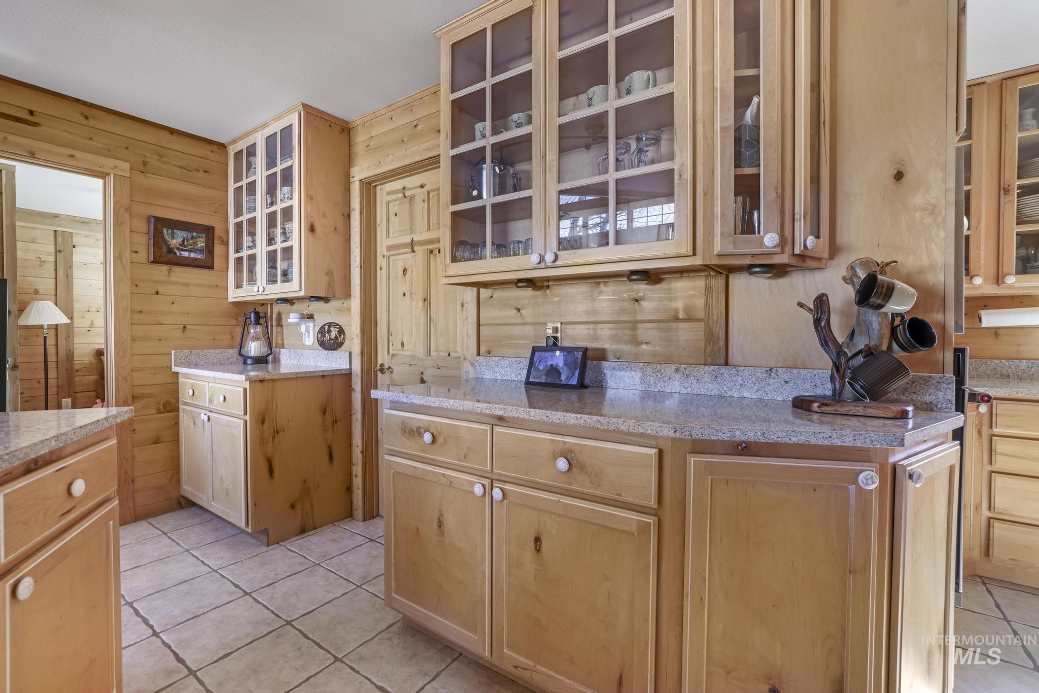 203 North Brush Road Fairfield, ID 83327 - Photo 12 of 50 Kitchen featuring wood walls, light tile patterned floors, glass insert cabinets, and light brown cabinetry