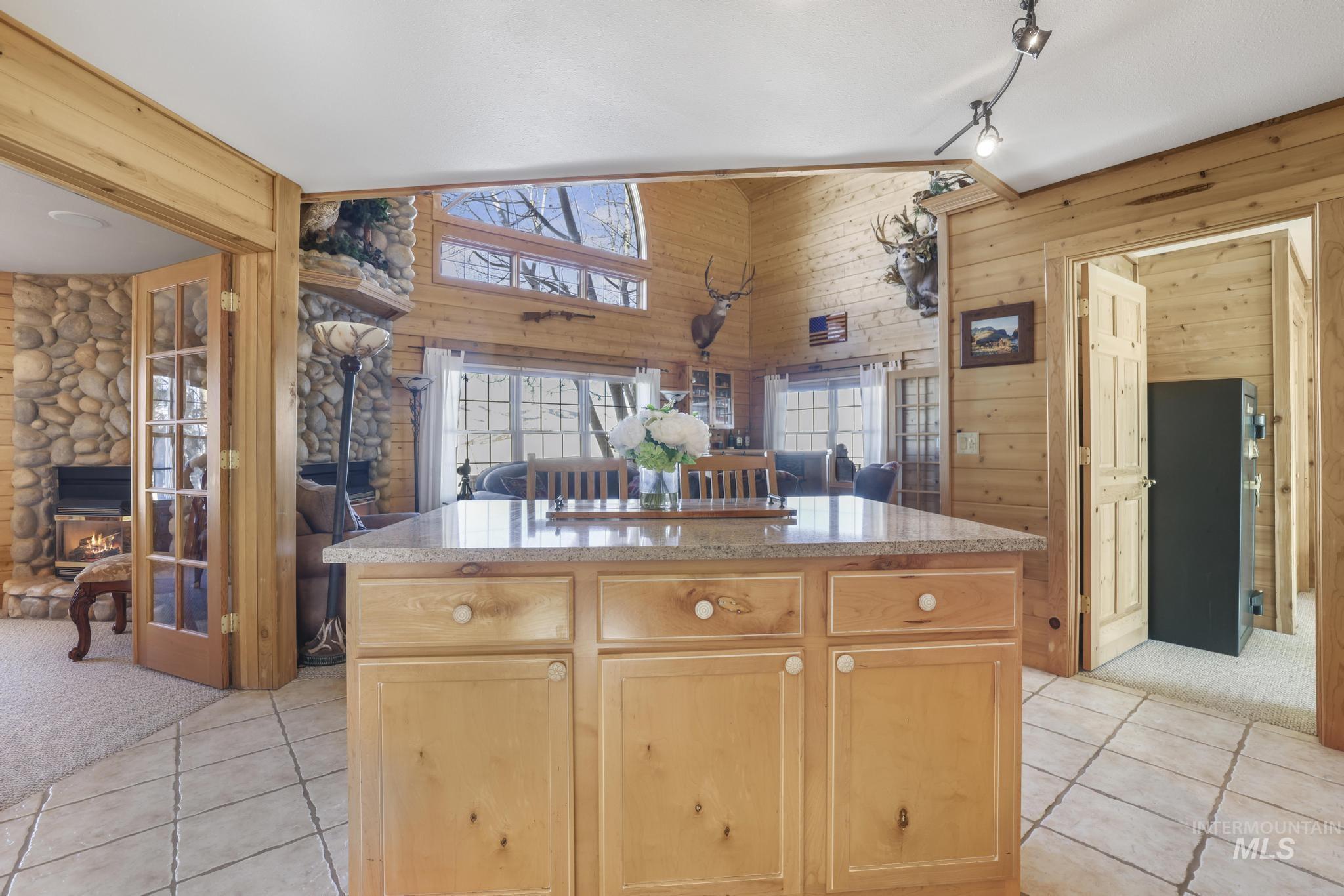 203 North Brush Road Fairfield, ID 83327 - Photo 49 of 50 Kitchen featuring light colored carpet, a stone fireplace, open floor plan, light tile patterned floors, and wooden walls