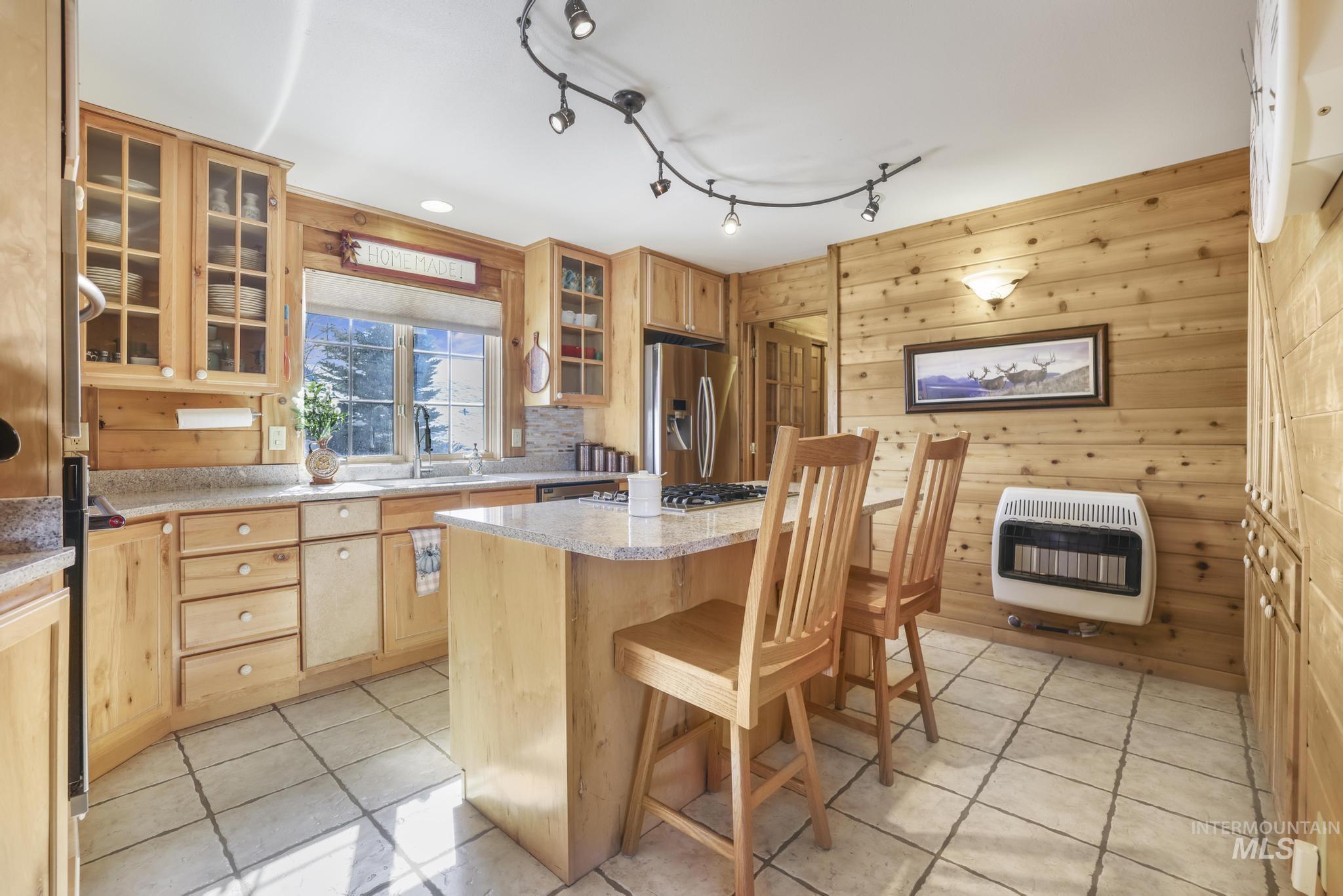 203 North Brush Road Fairfield, ID 83327 - Photo 13 of 50 Kitchen with wood walls, light tile patterned floors, a center island, heating unit, and glass insert cabinets