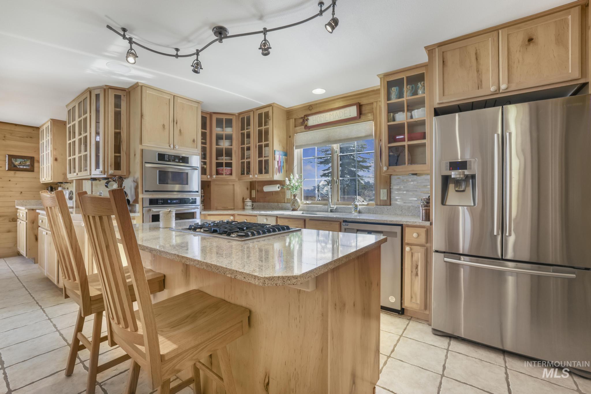 203 North Brush Road Fairfield, ID 83327 - Photo 14 of 50 Kitchen featuring stainless steel appliances, light tile patterned floors, glass insert cabinets, and a kitchen island