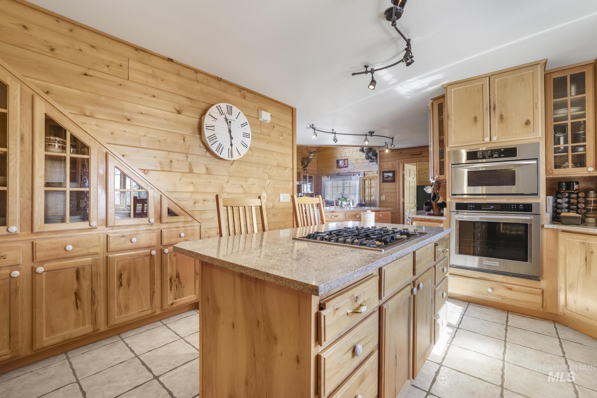 203 North Brush Road Fairfield, ID 83327 - Photo 15 of 50 Kitchen with light tile patterned floors, rail lighting, wooden walls, appliances with stainless steel finishes, and a center island