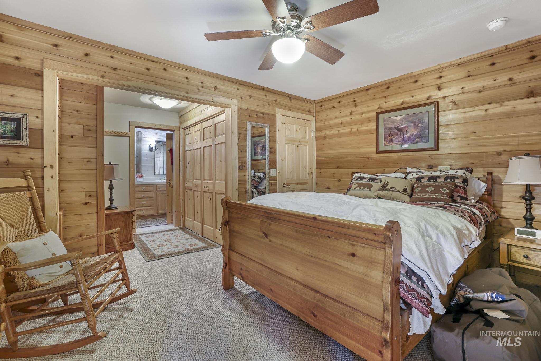 203 North Brush Road Fairfield, ID 83327 - Photo 17 of 50 Bedroom with light carpet, wooden walls, ensuite bathroom, and a ceiling fan