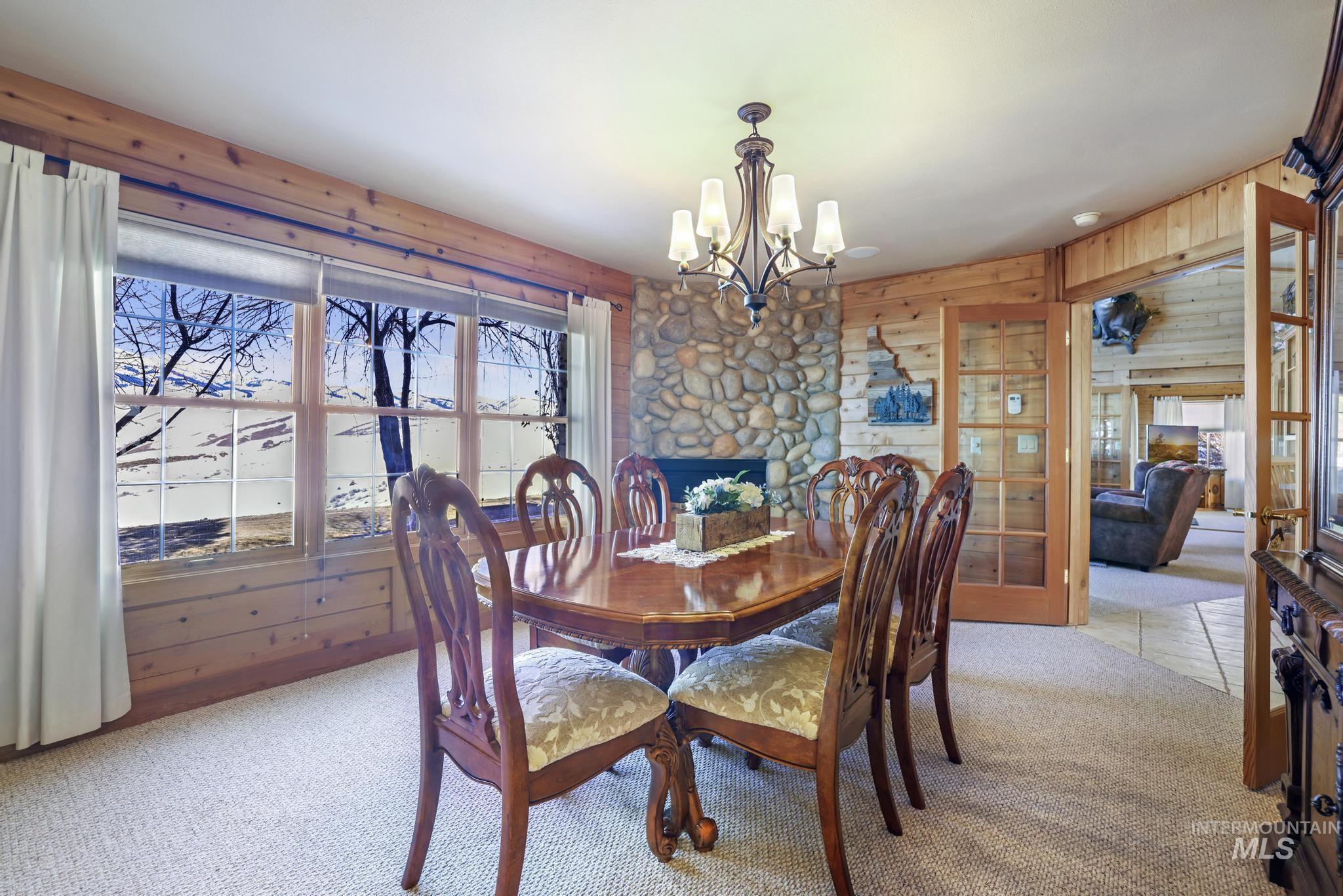 203 North Brush Road Fairfield, ID 83327 - Photo 23 of 50 Dining area with light carpet, a chandelier, and wooden walls