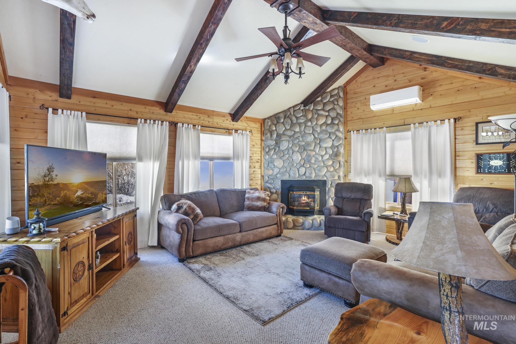 203 North Brush Road Fairfield, ID 83327 - Photo 24 of 50 Carpeted living room with wooden walls, a ceiling fan, a wall mounted air conditioner, and a fireplace