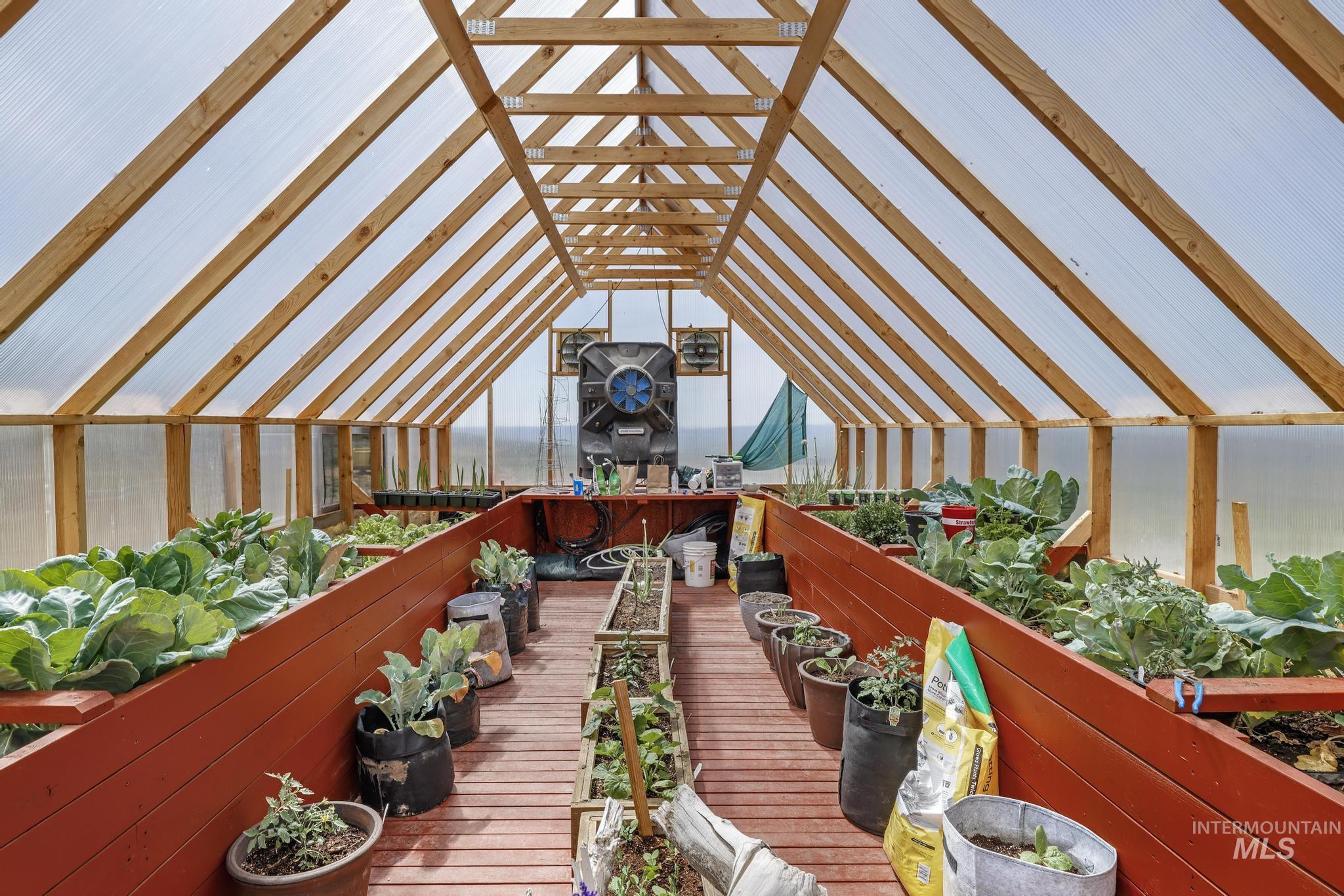 203 North Brush Road Fairfield, ID 83327 - Photo 31 of 50 Deck featuring a greenhouse and a vegetable garden