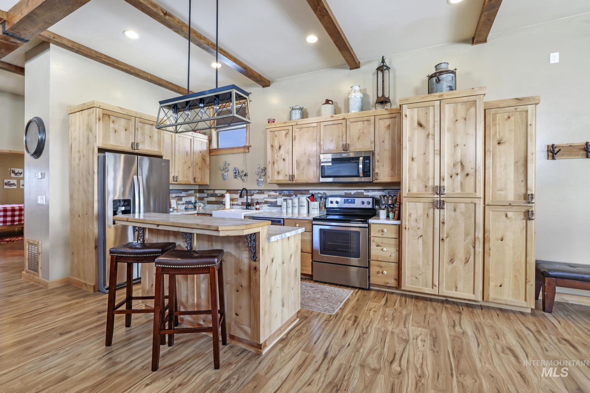 203 North Brush Road Fairfield, ID 83327 - Photo 45 of 50 Kitchen with light brown cabinets, appliances with stainless steel finishes, light countertops, a kitchen island, and a breakfast bar