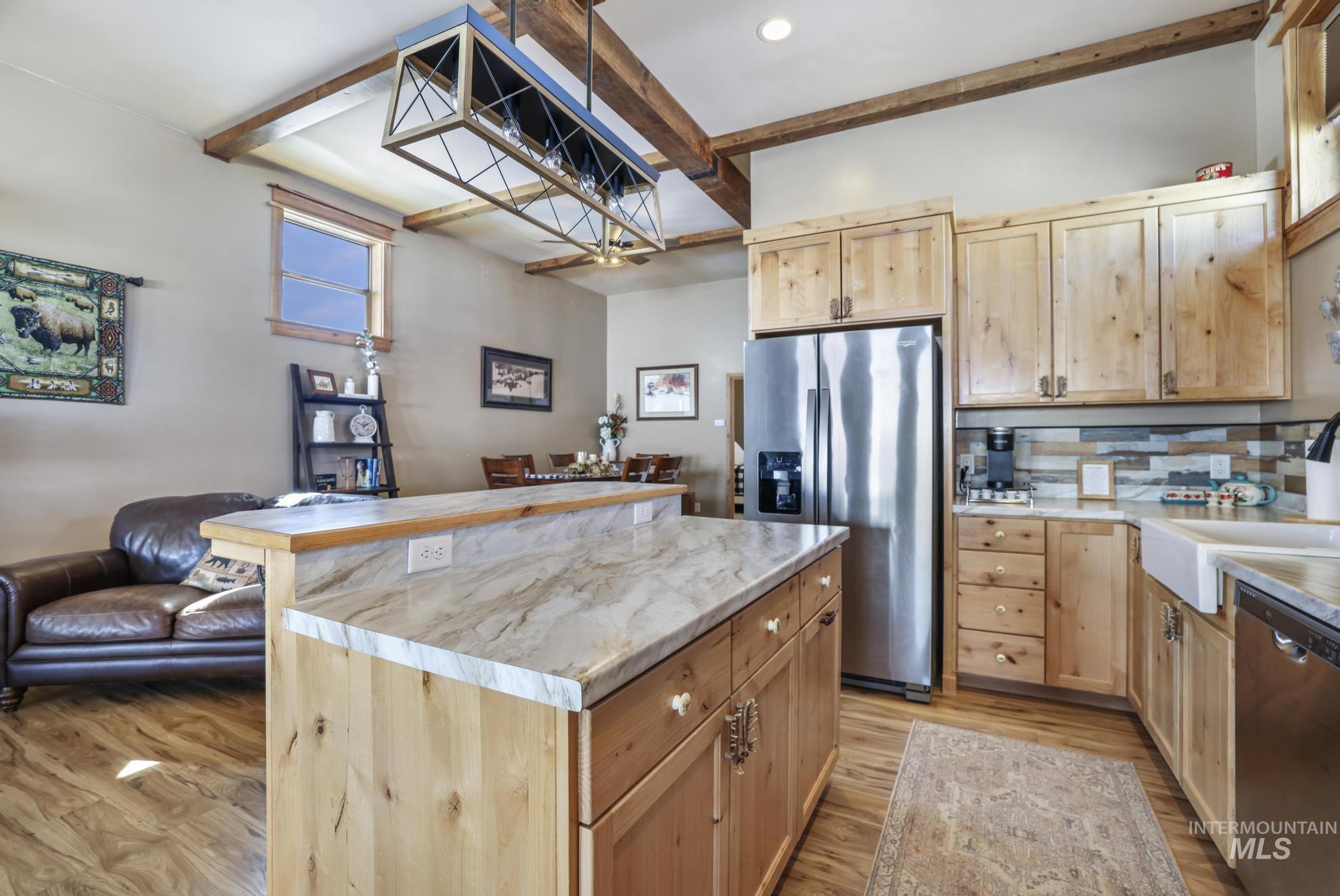 203 North Brush Road Fairfield, ID 83327 - Photo 50 of 50 Kitchen featuring light brown cabinets, stainless steel appliances, open floor plan, light wood-style flooring, and beamed ceiling