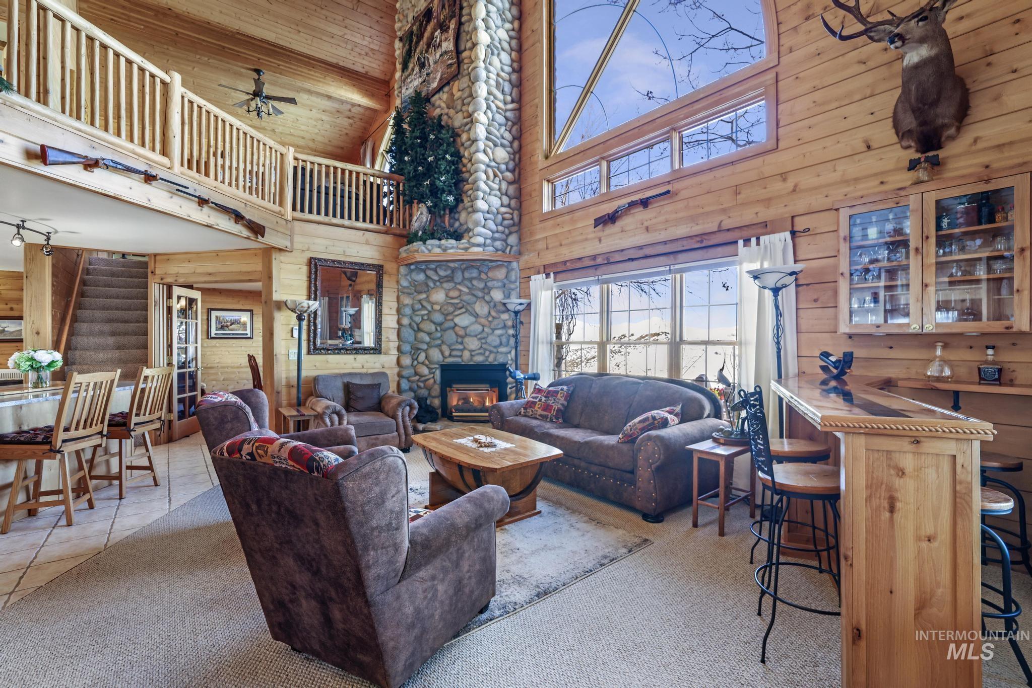 203 North Brush Road Fairfield, ID 83327 - Photo 7 of 50 Carpeted living area with wooden walls, stairway, a ceiling fan, a high ceiling, and wooden ceiling