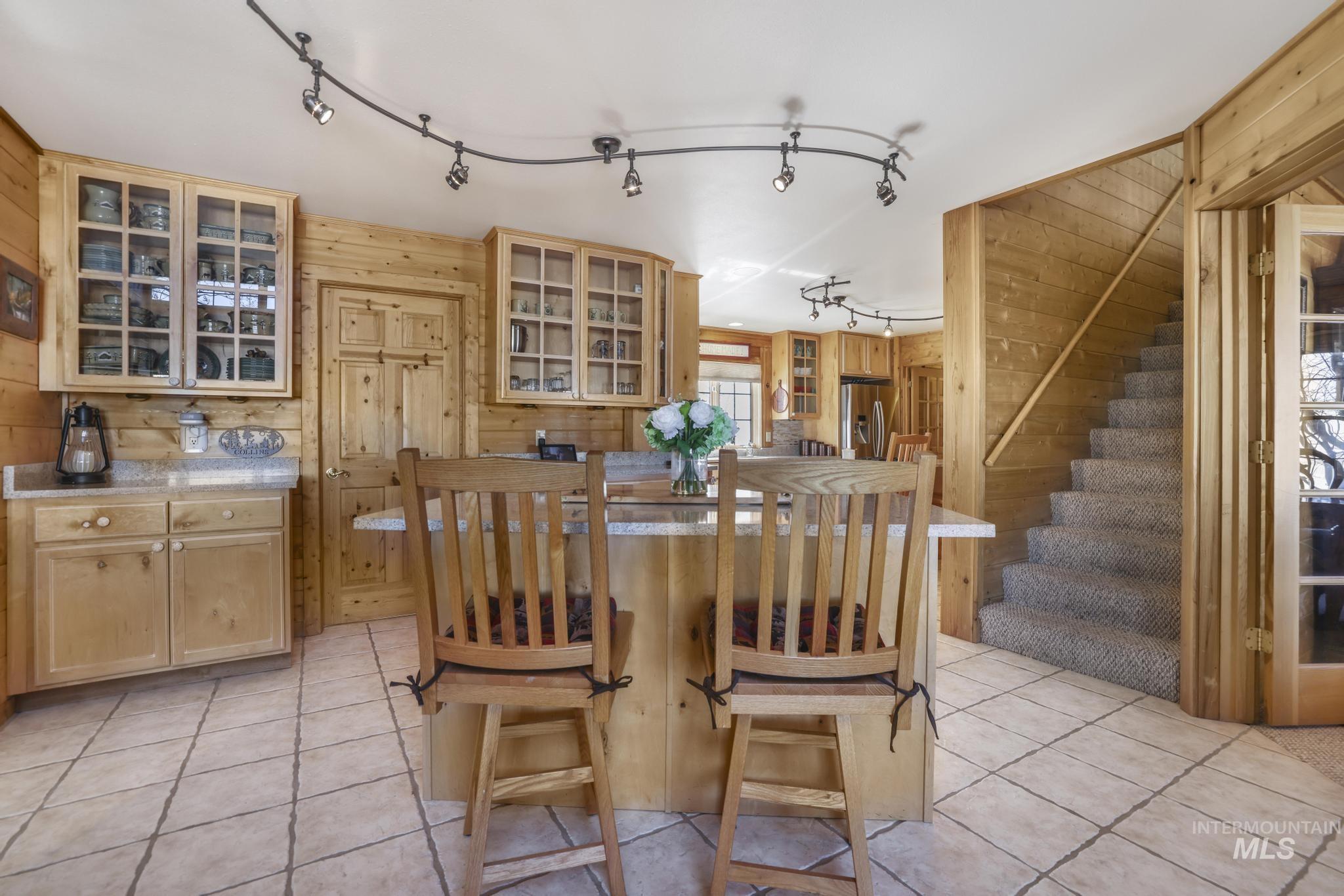 203 North Brush Road Fairfield, ID 83327 - Photo 10 of 50 Dining area featuring wood walls, light tile patterned floors, stairs, and rail lighting