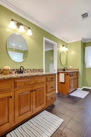 a bathroom with a granite countertop double vanity sink mirror and shower