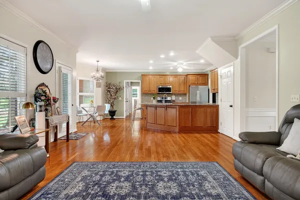 a kitchen with stainless steel appliances granite countertop a refrigerator a stove top oven and a dining table with wooden floor