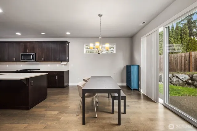 a kitchen with stainless steel appliances granite countertop a stove a refrigerator a sink dishwasher a dining table and chairs with wooden floor