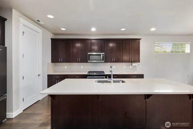 a kitchen with stainless steel appliances a sink a stove a microwave and wooden cabinets