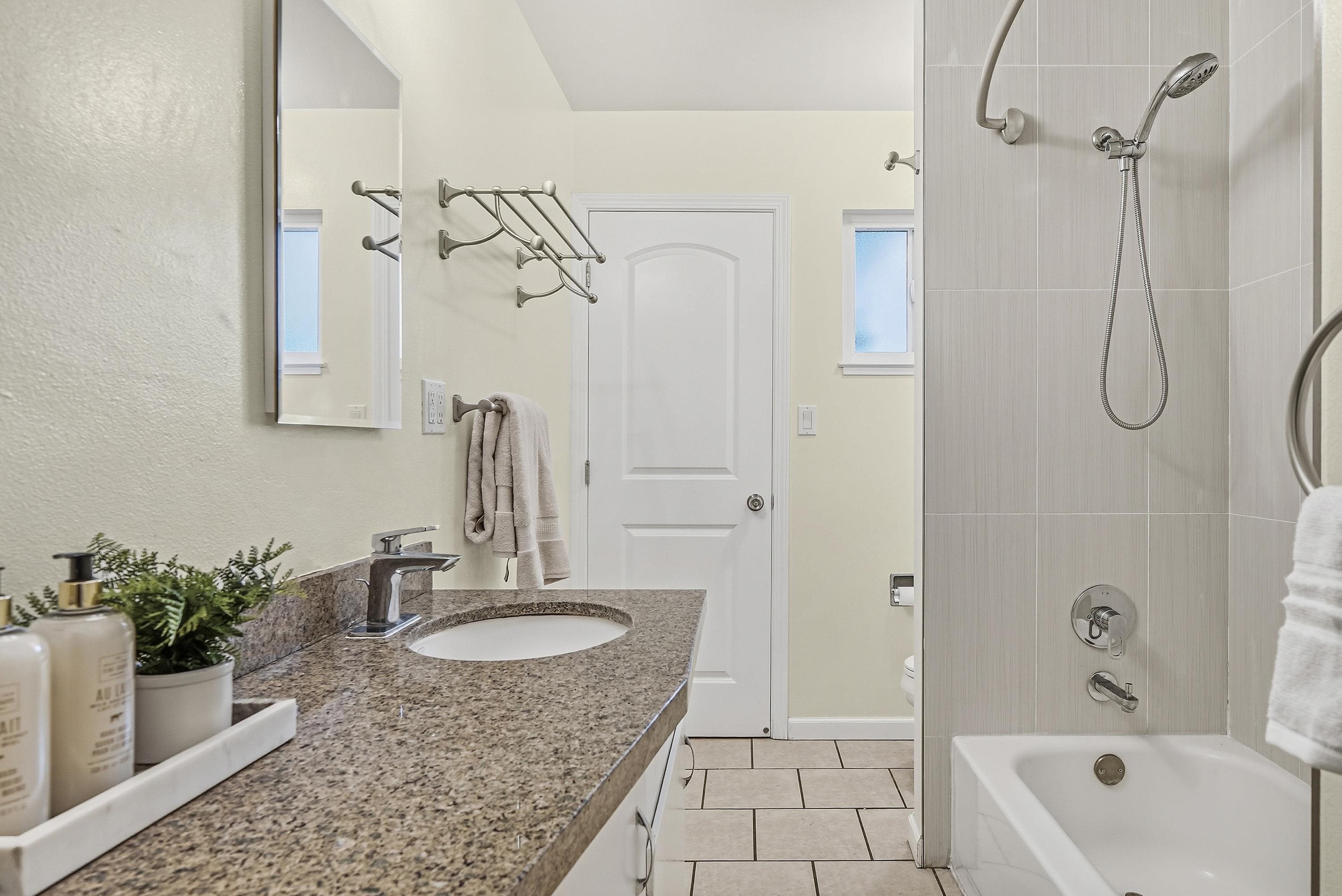 4214 Wells Street Pleasanton, CA 94566 - Photo 30 of 38 a bathroom with a granite countertop sink a mirror a vanity and shower