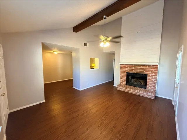 a view of an empty room with wooden floor fireplace and a window