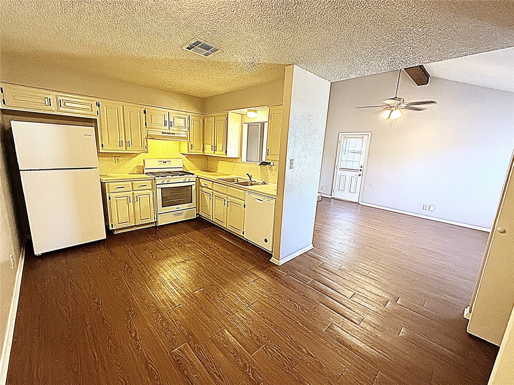 12800 Tomanet Trail, Unit B Austin, TX 78727 - Photo 5 of 12 a kitchen with wooden floors and white appliances