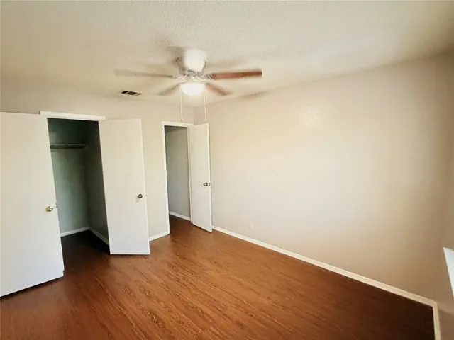 an empty room with wooden floor and ceiling fan