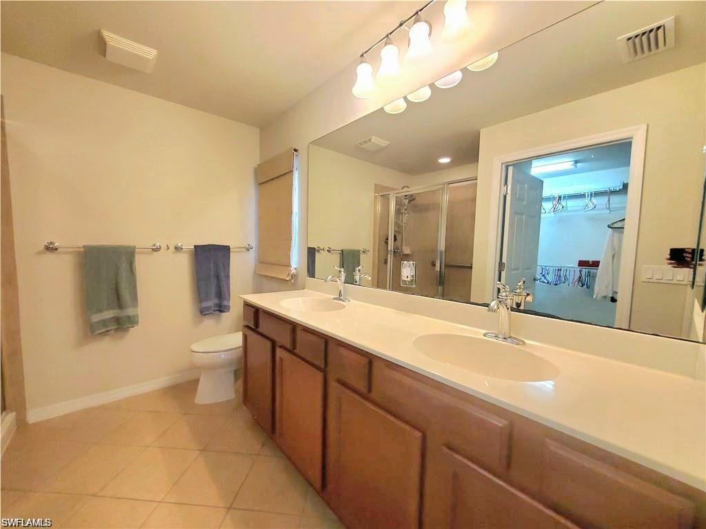 8657 Querce Court Naples, FL 34114 - Photo 9 of 44 a spacious bathroom with a granite countertop sink a toilet a mirror and shower