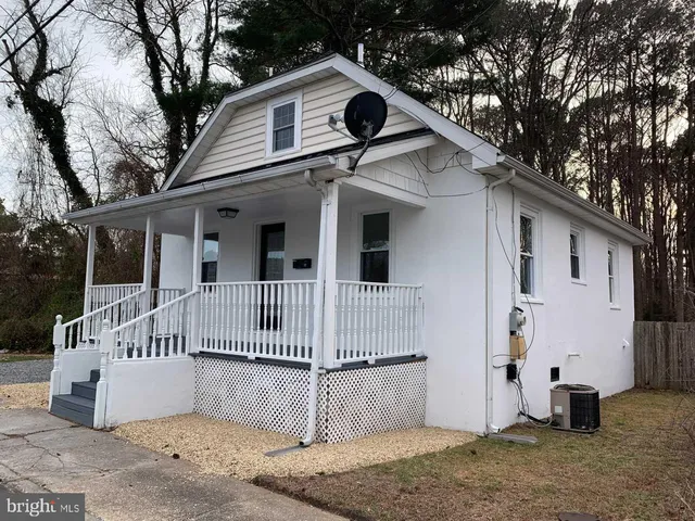 a view of a white house with a small yard and large tree