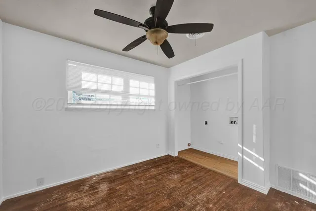 a view of empty room with wooden floor and fan