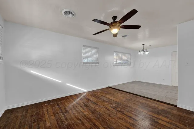 a view of empty room with wooden floor and ceiling fan