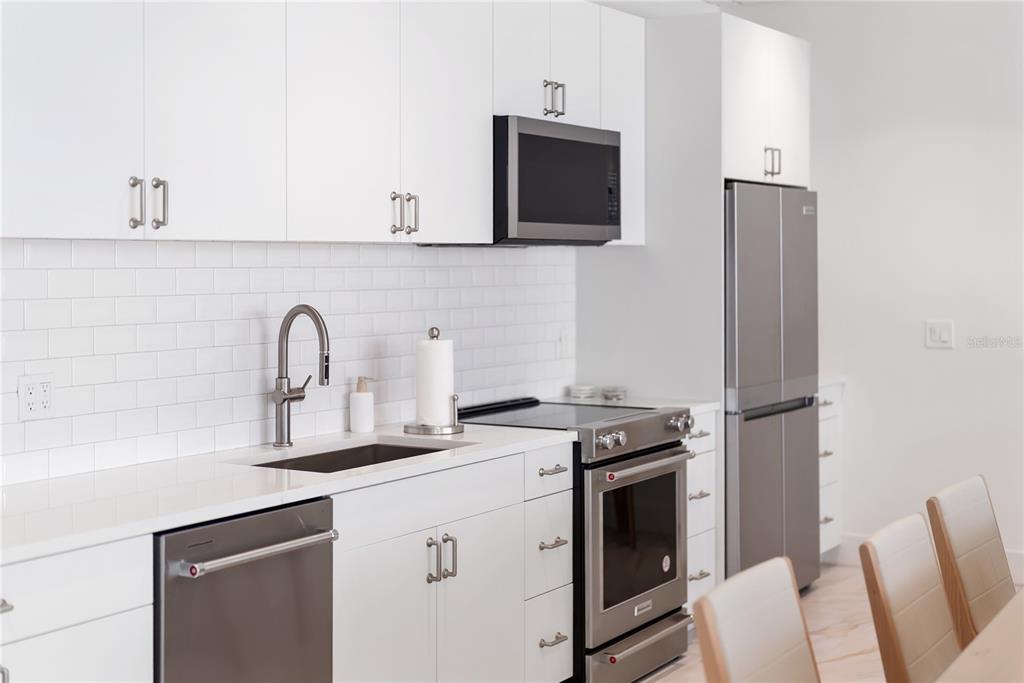 1750 Benjamin Franklin Drive, Unit 6G Sarasota, FL 34236 - Photo 12 of 82 a kitchen with stainless steel appliances white cabinets and a stove top oven