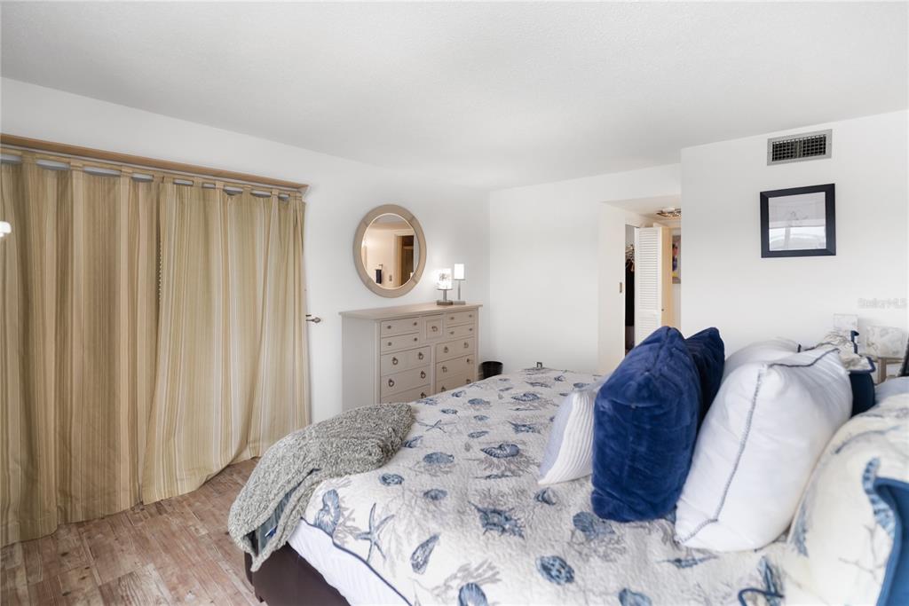 1750 Benjamin Franklin Drive, Unit 6G Sarasota, FL 34236 - Photo 26 of 82 a bed sitting in a bedroom and dresser with wooden floor