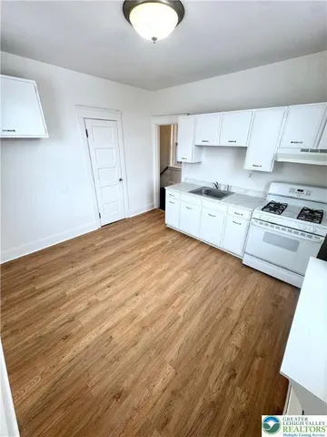 a large kitchen with cabinets wooden floor and stainless steel appliances