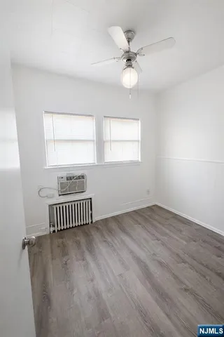 an empty room with wooden floor fan and windows