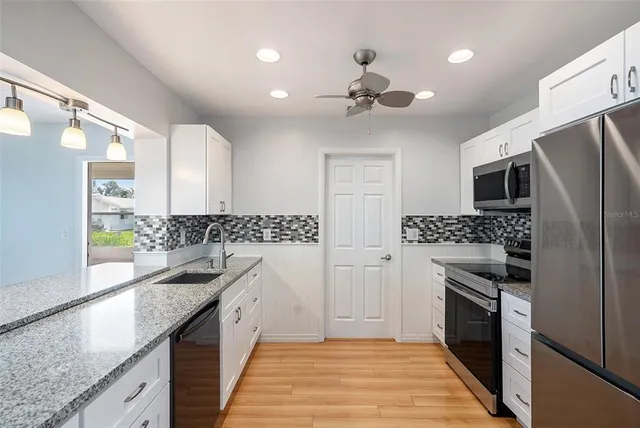 a modern kitchen with stainless steel appliances granite countertop a refrigerator a sink a stove and dishwasher