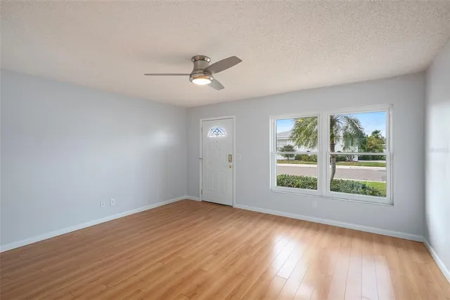 a view of empty room with wooden floor and fan