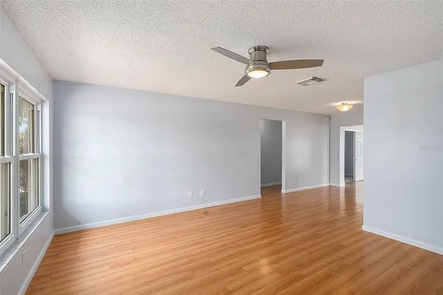 a view of empty room with wooden floor and fan