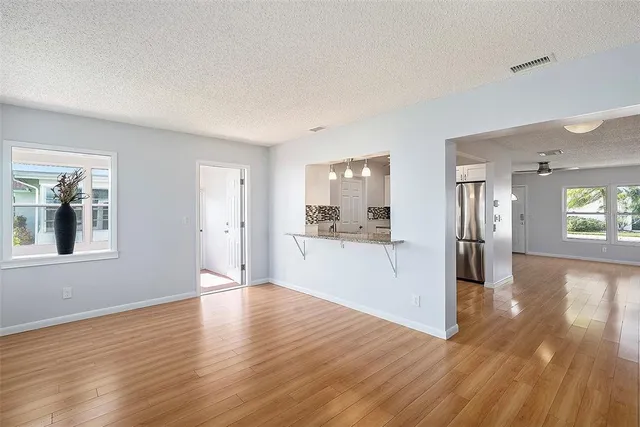 a view of a big room with wooden floor and a kitchen