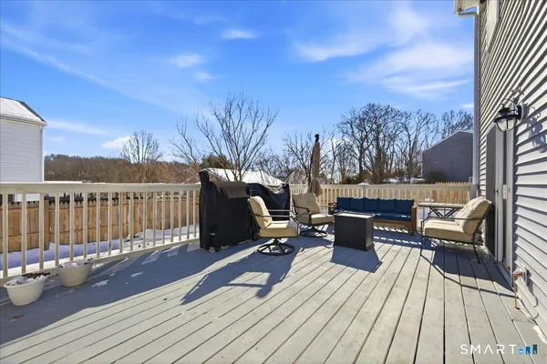 a view of a roof deck with table and chairs a barbeque with wooden floor and fence