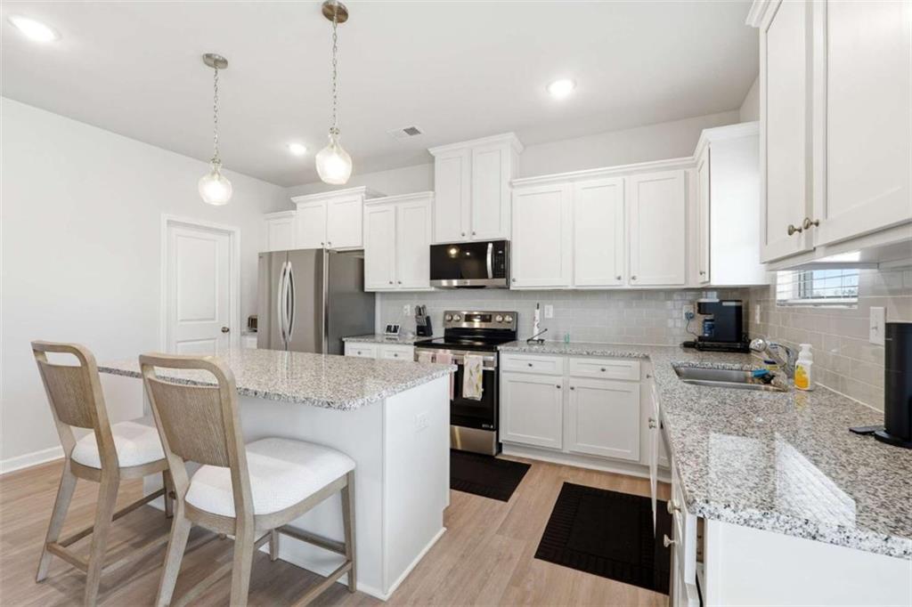 11817 Rizvan Place Covington, GA 30014 - Photo 16 of 40 a kitchen with white cabinets and stainless steel appliances